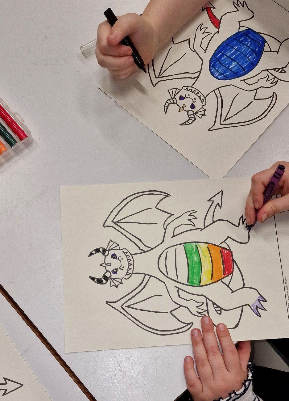 Children colouring dragon drawings at a workshop table
