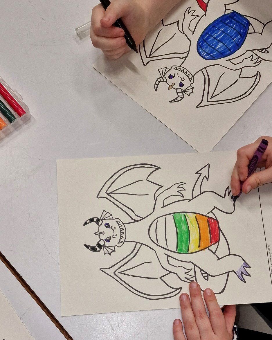 Children colouring dragon drawings at a workshop table