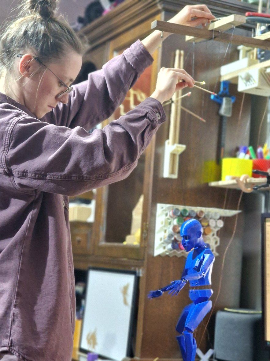 Working a blue articulated marionette with a wooden control bar