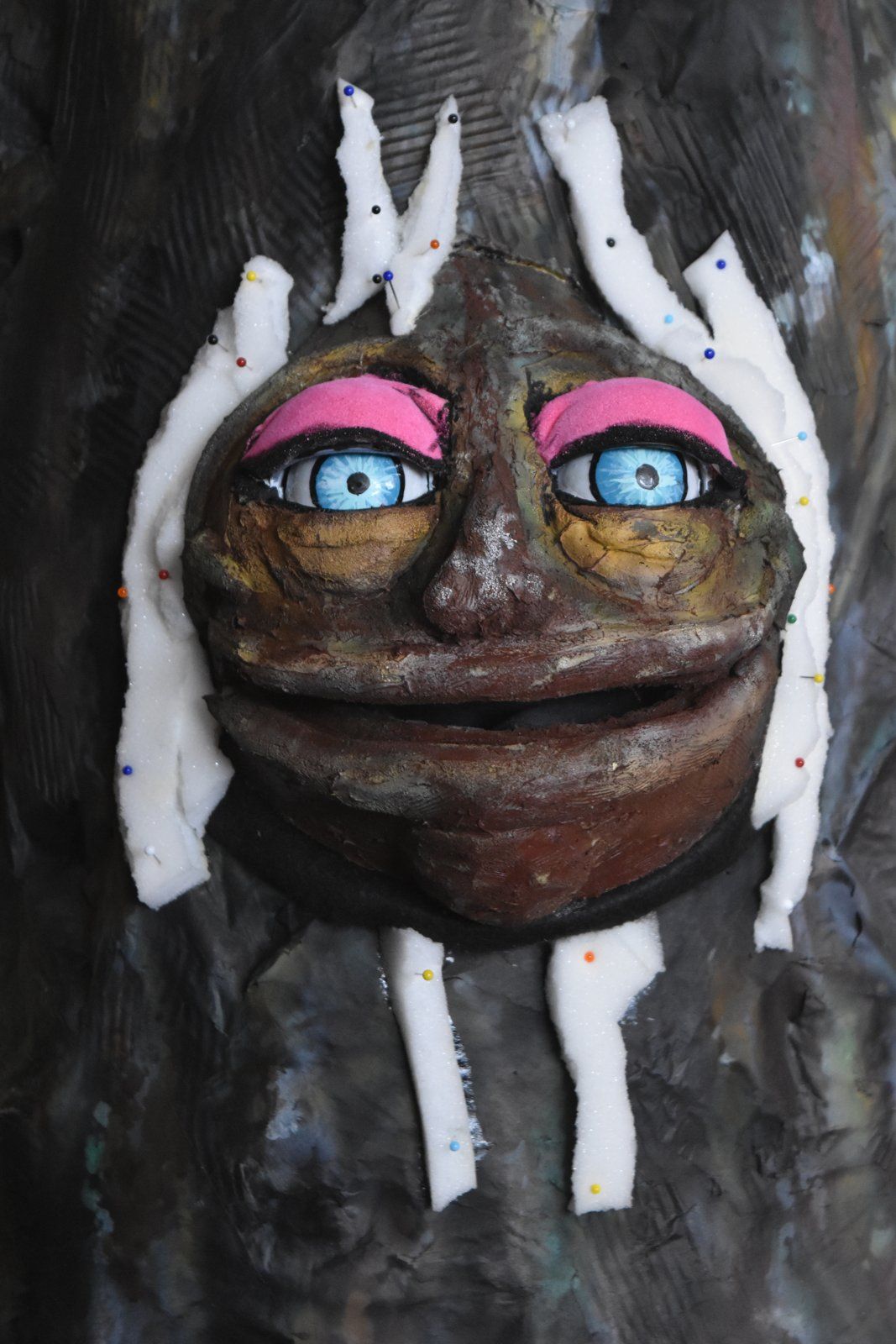 A face cut free from the tree, with fabric around the edge.