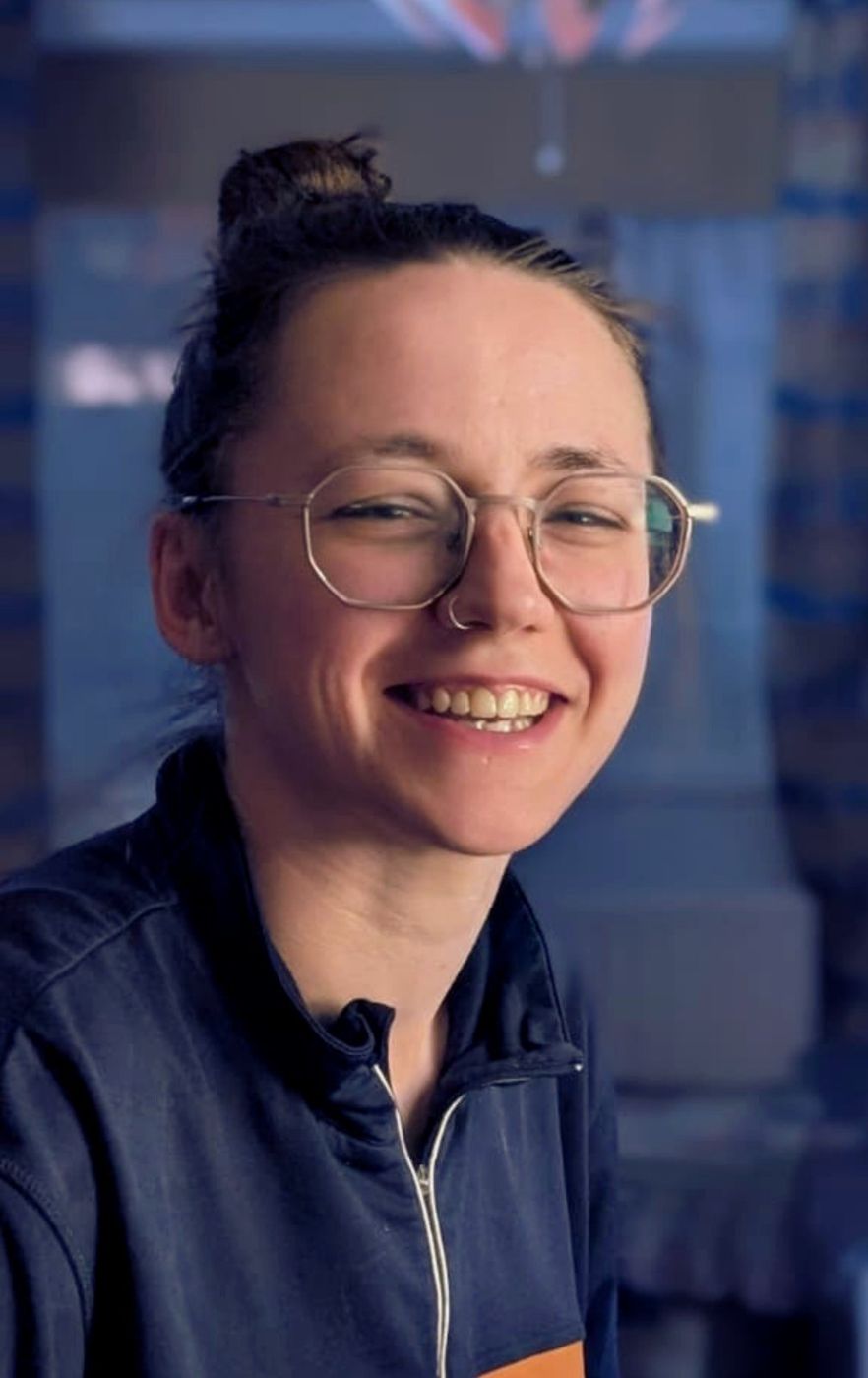 Portrait of Mhairi Anderson, smiling, wearing glasses and a navy jacket