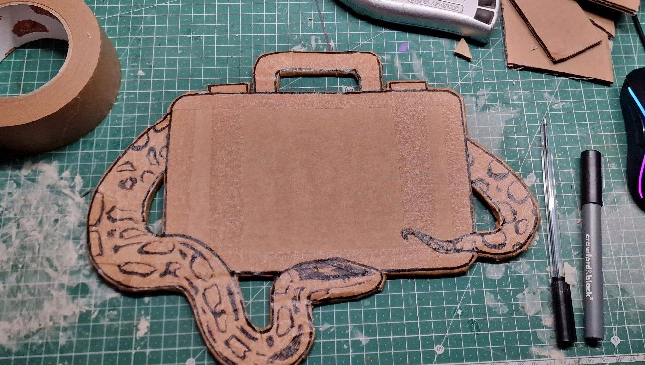 Cardboard suitcase prop with a drawn snake wrapped around it