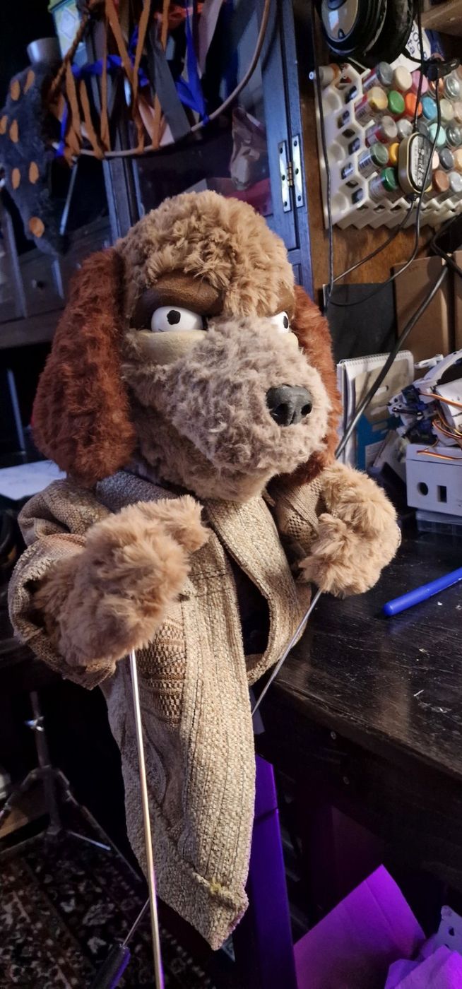 Scout, a brown dog hand-and-rod puppet with a knitted jacket