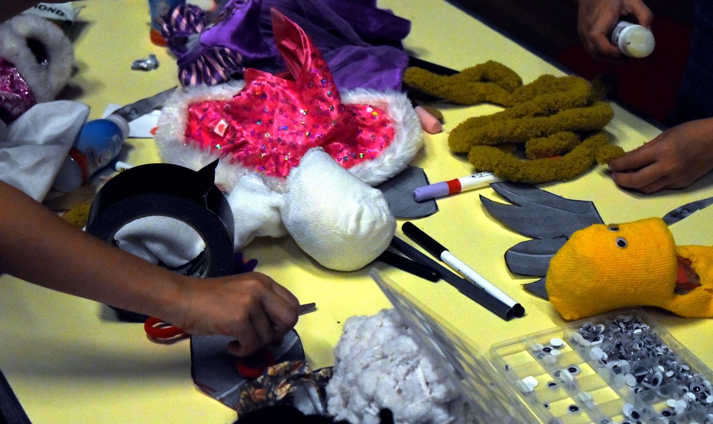 Sock puppets and making materials spread across a workshop table