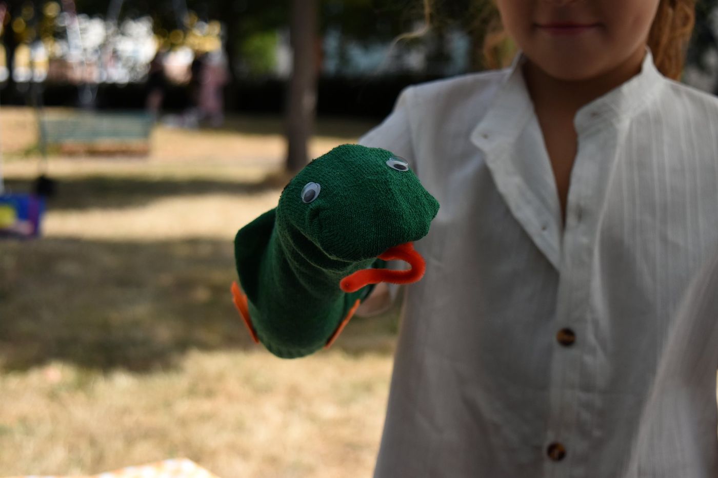 Green sock puppet with googly eyes held toward the camera